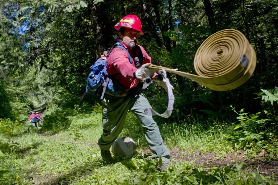 Larch Corrections Center inmate Eric Rodriguez unfurls a rolled hose during a training exercise for the prison’s wildland firefighting program. Larch has an inmate work crew that fights fires and works on land management projects around the region.