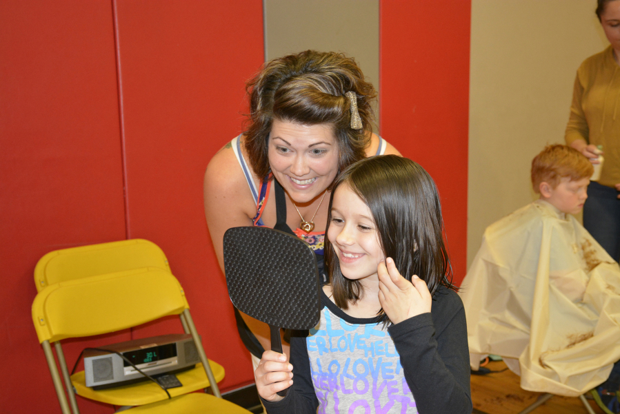 Washougal: Emily Thompson of Urban Style, left, shows Hathaway Elementary School first-grader Izzabella Lucus her new haircut, which Izzabella received during the second Hathaway Elementary School Booster Club Cuts for Kids program.
