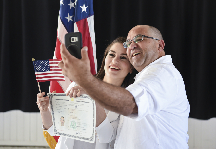 Heylen Medina, 25, poses for a photo holding her certificate of naturalization with her father, Lazaro Medina, following a naturalization ceremony for new American citizens at Pearson Air Museum on Friday. Lazaro left Cuba on a raft, gaining citizenship in the United States in 2005. His daughter, Heylen, immigrated to Vancouver from Cuba at the age of 18.