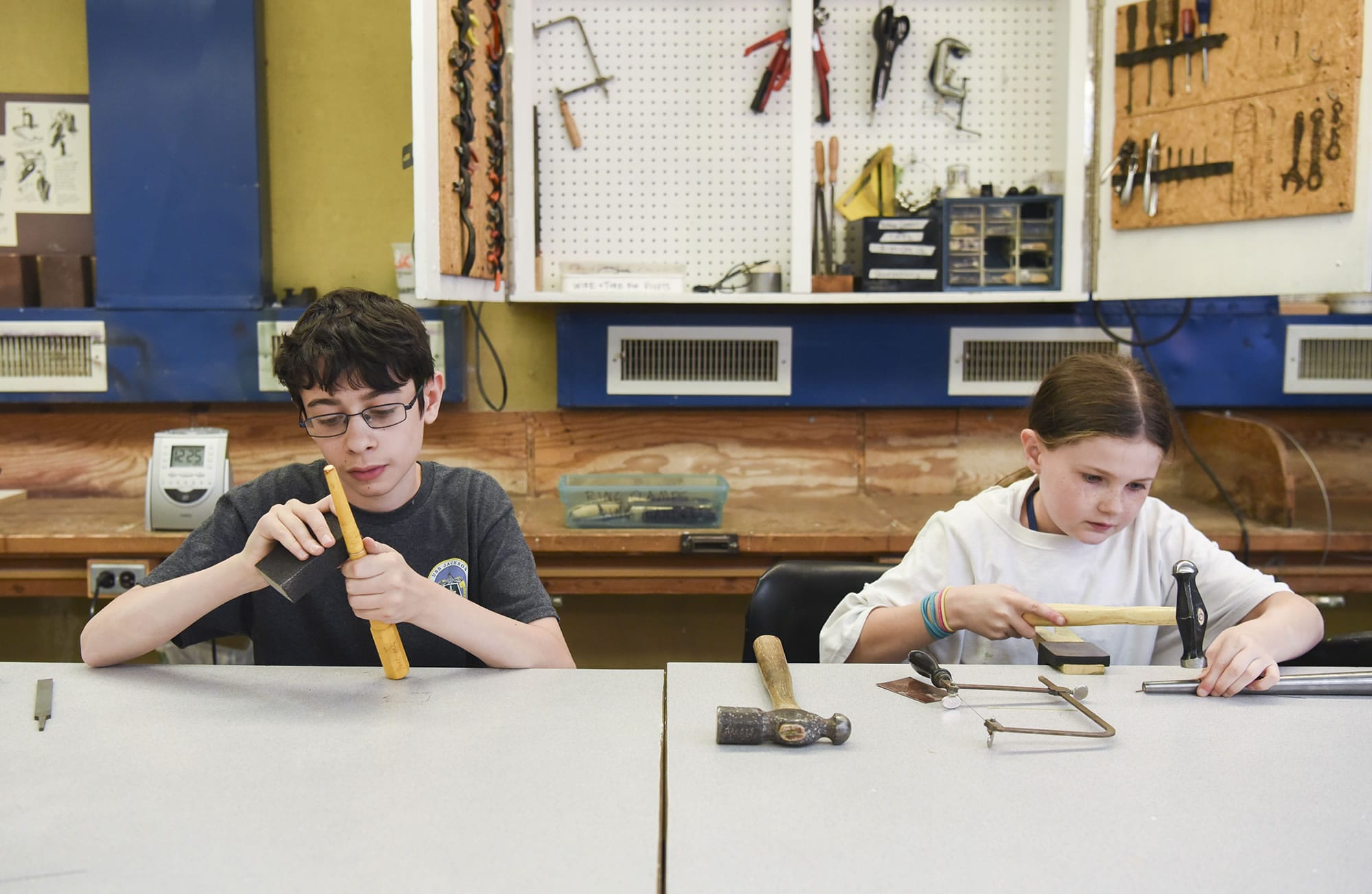 Sam Corio, 13, left, and Emily Rodengren, 10, make careful adjustments Tuesday to rings they made in a metal arts class at Art College, a summer camp at Clark College for students ages 9-14.
