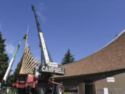 A crane holds a cross over the roof of First Congregational United Church of Christ in Hazel Dell while workers in a construction basket secure it into place.