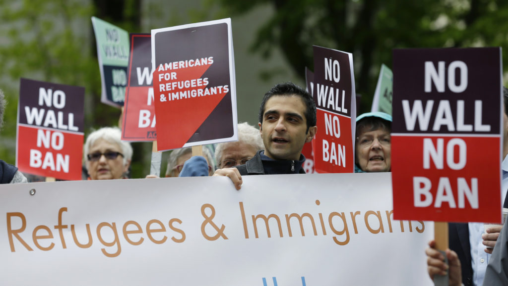 FILE--In this May 15, 2017, file photo, protesters hold signs during a demonstration against President Donald Trump's revised travel ban, Monday, May 15, 2017, outside a federal courthouse in Seattle. A three-judge panel of the 9th U.S. Circuit Court of Appeals on Monday upheld a decision to block the revised travel ban, which would suspend the nation's refugee program and temporarily bar new visas for citizens of Iran, Libya, Somalia, Sudan, Syria and Yemen. (AP Photo/Ted S.