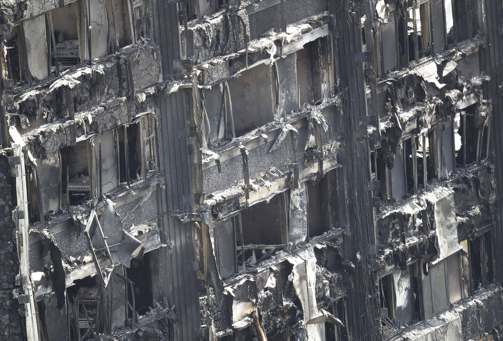 Part of the scorched facade of the Grenfell Tower in London as firefighting continue to damp-down the deadly fire, Thursday, June 15, 2017.  A massive fire raced through the 24-storey high-rise apartment building in west London early Wednesday, and London fire commissioner says it will take weeks for the building to be searched and 'cleared'.