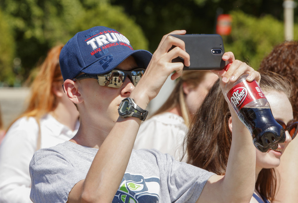 Bryce Howard, 15, of Everett, Wash., wears a Trump hat as he snaps a photo during a visit to the Supreme Court in Washington, Monday, June 26, 2017, where justices issued their final rulings for the term. The high court is letting a limited version of the Trump administration ban on travel from six mostly Muslim countries take effect, a victory for President Donald Trump in the biggest legal controversy of his young presidency. (AP Photo/J.