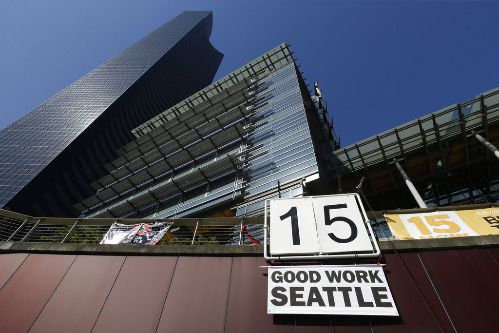 FILE - In this June 2, 2014, file photo, a sign that reads "15 Good Work Seattle" is displayed below Seattle City Hall, right, and the Columbia Center building, left, after the Seattle City Council passed a $15 minimum wage measure. Seattle's $15-an-hour minimum wage law has cost the city jobs, according to a study released Monday, June 26, 2017, that contradicted another new study published last week. (AP Photo/Ted S.