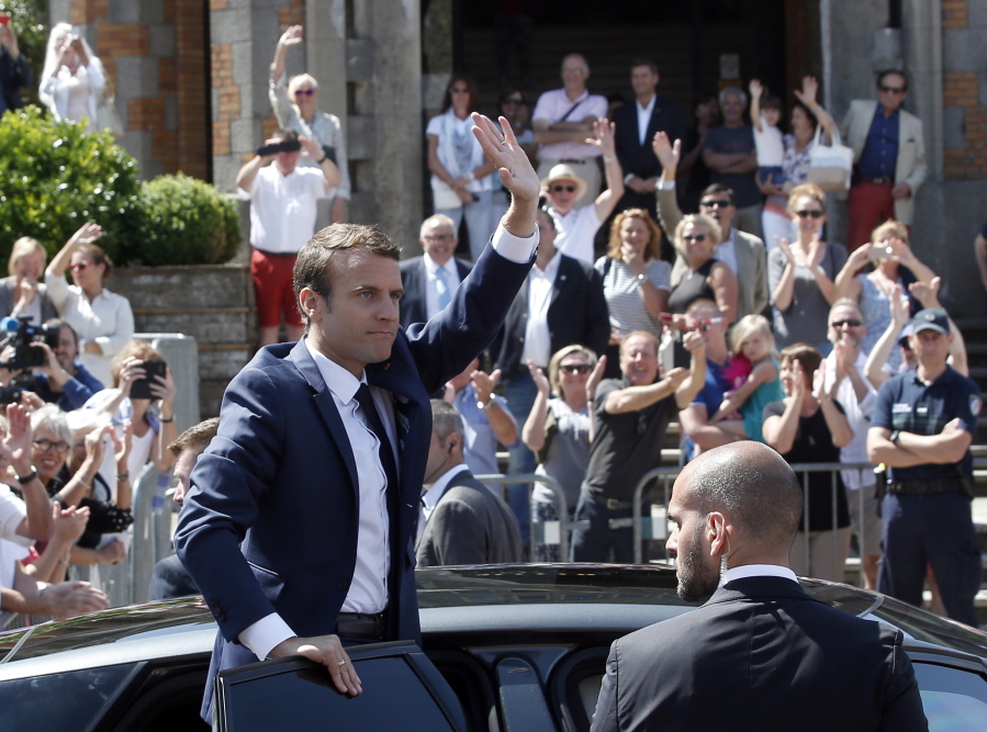 French President Emmanuel Macron waves to the audience as he leaves a polling station in Le Touquet, northern France, after casting his vote in the first round of the two-stage legislative elections on Sunday. French voters are choosing legislators in the first round of parliamentary elections, with President Emmanuel Macron’s party “Republic on the Move” hoping to win a strong majority in the National Assembly to push through bold labor and security reforms.