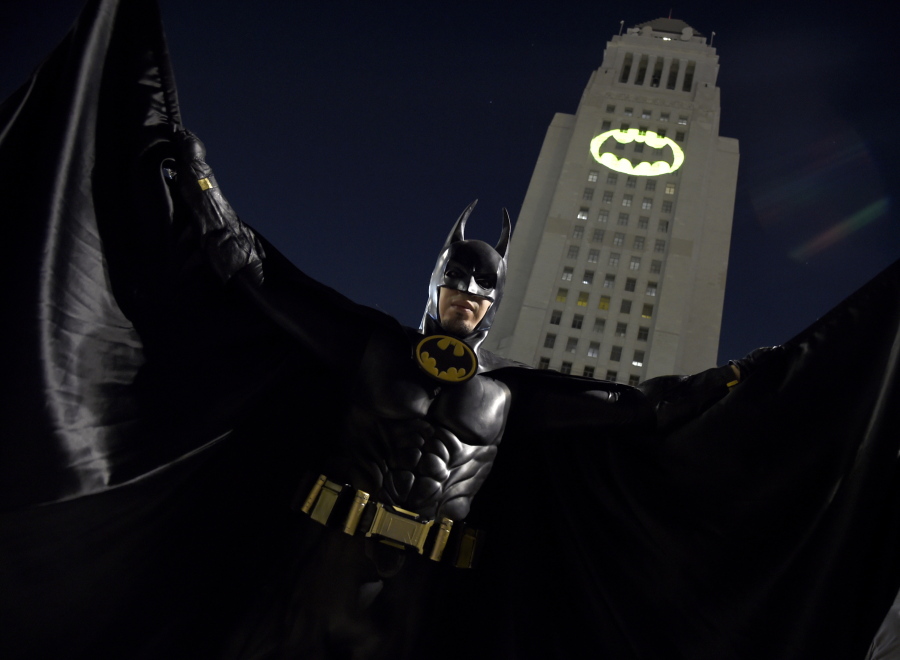 A man poses in front of a Bat-Signal projected onto City Hall at a tribute to “Batman” star Adam West on Thursday in Los Angeles.