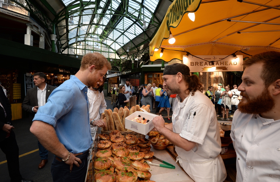 Britain’s Prince Harry, left, buys doughnuts as he tours stalls June 15 during a visit to Borough Market, near London Bridge, which had opened the day before for the first time since the London Bridge terrorist attacks.