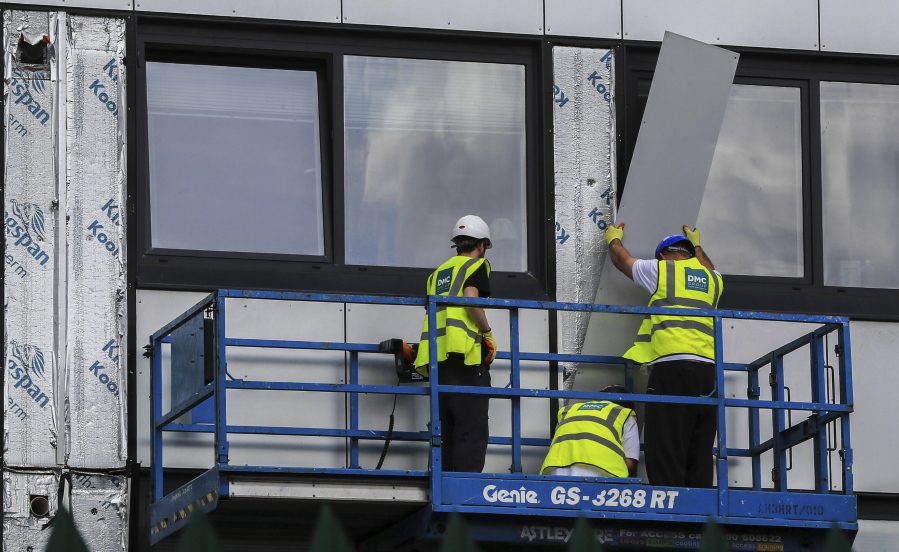 Workers remove cladding from Whitebeam Court, in Pendleton, Manchester on Monday. The list of high-rise apartment towers in Britain that have failed fire safety tests grew to 60, officials said Sunday, revealing the mounting challenge the government faces in the aftermath of London’s Grenfell Tower fire tragedy.