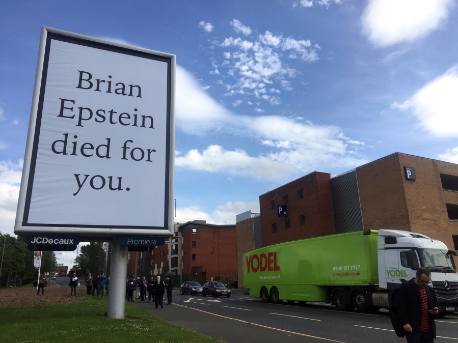 Vehicles drive past a billboard June 1, 2017, referring to the late Beatles manager Britain Epstein, created by artist Jeremy Deller, in Liverpool, England. The work is part of a festival in the city celebrating the 50th anniversary of the Beatles album “Sgt.