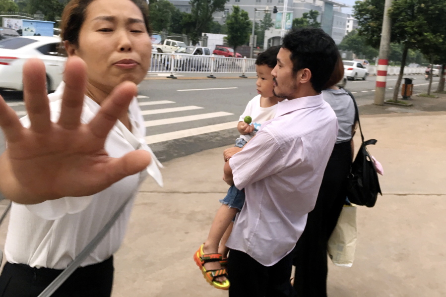 Hua Xiaoqin, left, sister of Chinese labor activist Hua Haifeng, tries to block a reporter approaching Hua Haifeng, right, as he carries his son Bobo leaves a police station after being released in Ganzhou in southern China’s Jiangxi Province, Wednesday, June 28, 2017. Chinese authorities have released on bail three activists who had been detained after investigating labor conditions at a factory that produced shoes for Ivanka Trump and other brands.