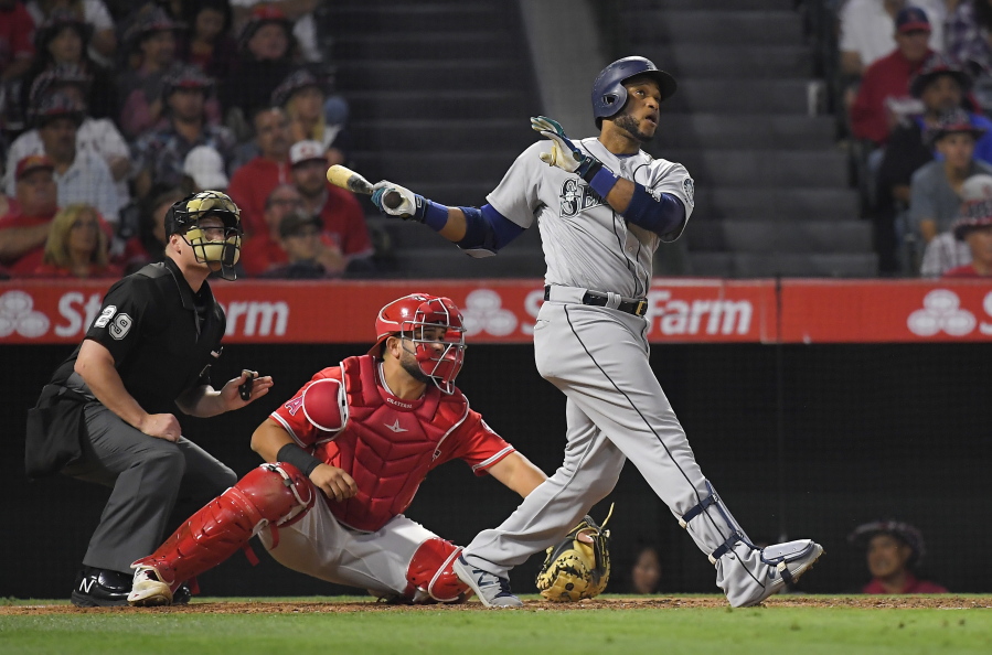 Seattle Mariners’ Robinson Cano, right, hits a three-run home run as Los Angeles Angels catcher Juan Graterol, center, watches along with home plate umpire Sean Barber during the fifth inning of a baseball game, Friday, June 30, 2017, in Anaheim, Calif. (AP Photo/Mark J.
