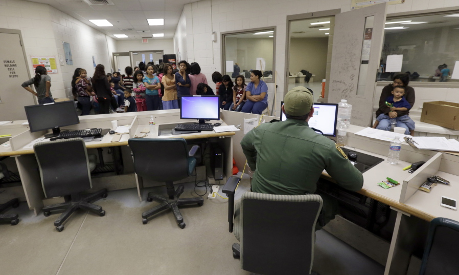 FILE - This June 18, 2014, file photo shows U.S. Customs and Border Protection agents work at a processing facility in Brownsville,Texas. A new "surge initiative" aims to identify and arrest the adult sponsors of unaccompanied minors who paid coyotes or other smuggling operations to bring young people across the U.S. border, Immigration and Customs Enforcement officials confirmed Thursday, June 29, 2017.