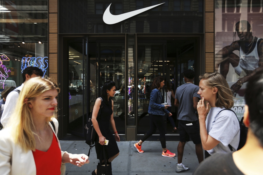 Pedestrians walk by the Nike Soho store, Thursday, June 15, 2017, in the SoHo neighborhood of New York. Nike said Thursday that it plans to sell more shoes directly to customers online as part of a restructuring in which it plans to cut about 1,400 jobs. It will also reduce the number of sneaker and clothing styles it makes by a quarter and focus on hot sellers.