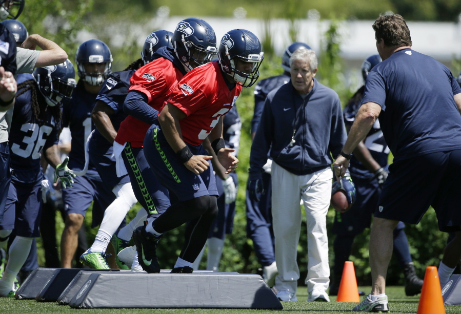 Seattle Seahawks head coach Pete Carroll looks on as Seattle Seahawks quarterback Russell Wilson, center, takes part in a drill during practice, Friday in Renton. Ted S.