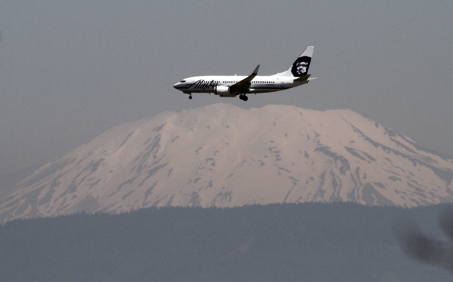 Mount St. Helens is seen through a layer of smog as an Alaska Airlines plane comes in for a landing at Portland International Airport in Portland. Alaska Airlines is offering a charter flight off the Oregon Coast during the solar eclipse Aug. 21 that will allow select passengers to view the astronomical event from the sky.