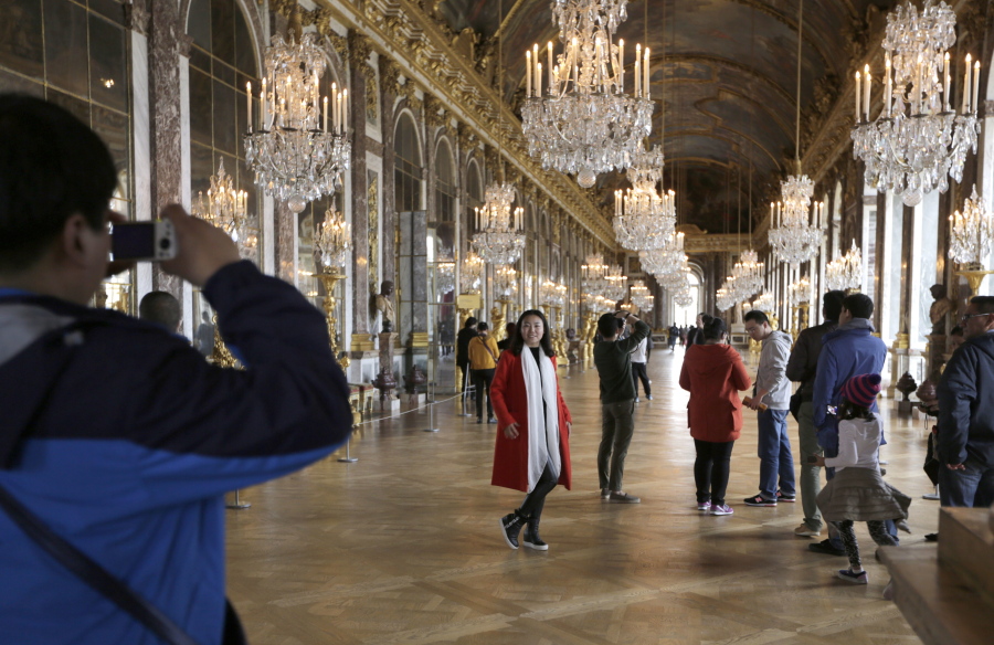 Visitors pose inside the Hall of Mirrors in the Versailles castle in Versailles, west of Paris, on Nov. 17, 2015. Rick Steves’ summer travel tips include getting tickets in advance for major attractions so you can skip the line and avoid the crowds.