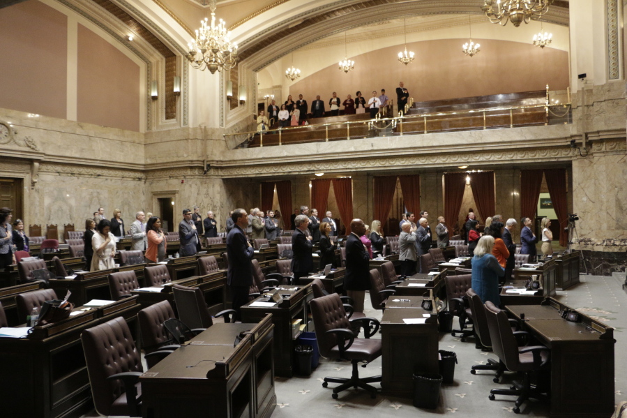 Lawmakers at the House stand during the Pledge of Allegiance on Tuesday in Olympia. The Legislature must send a new two-year budget this week or else risk a partial government shutdown.