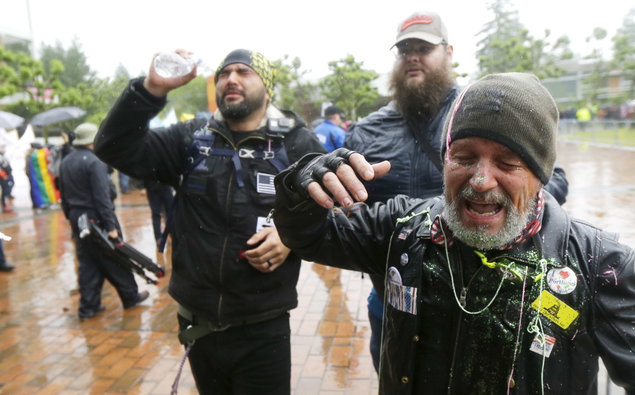 Two men protesting with the conservative group Patriot Prayer react after they said they were sprayed with pepper spray and doused with glitter by counter-protesters Thursday at Evergreen State College in Olympia. (AP Photo/Ted S.