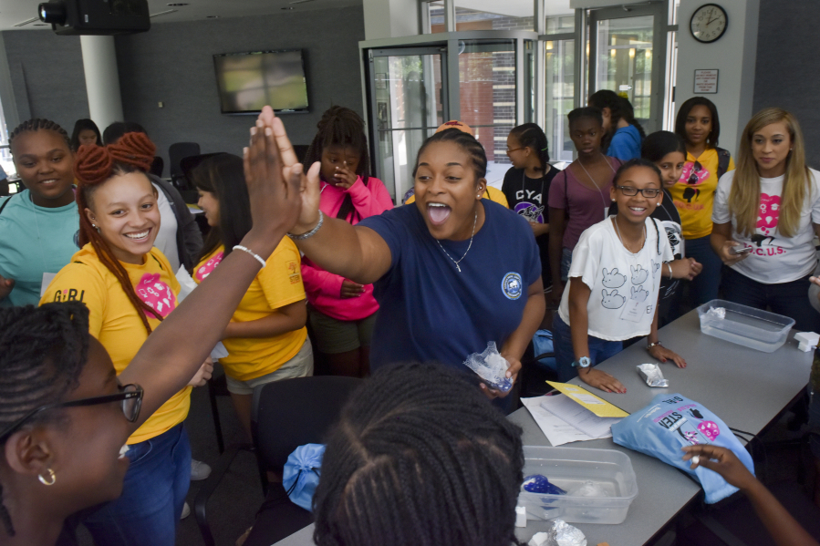 Ann-Audrey Ezi, left, gets a high-five from Amber Smith-St. Louis of the Norfolk Navy Shipyard after Ezi’s floating aluminum foil structure held the most marbles, 27, before sinking during a naval engineering session at FOCUS camp at George Mason University on June 28, 2017 in Fairfax, Virginia. The camp is designed to expose middle school-aged females of color to a variety of disciplines in science, technology, engineering and mathematics.