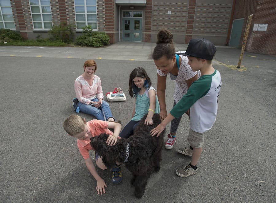 Eli Cantwell, 6, bonds with therapy dog Luna, a 7-month-old goldendoodle, while joined by his mom, dog handler Melissa Cantwell, from left, India Woods, 9, Zaiah Sloan, 9, and Ian Brakefield, 7, at Hough Elementary School on Thursday afternoon. Cantwell is a special education teacher at the school and advocated for the purchase of the dog to provide comfort for students. Luna will work across campus with all students. The kids were at the Vancouver school to participate in a summer camp.