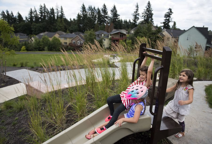 Camas residents Milan Turnbull, 6, swings onto the slide next to Halle Iverson, 6, as Marina Carlson, 6, waits for her turn behind them at Cooper’s View Park in Camas. A recent survey found residents think the city should improve parks and streets.