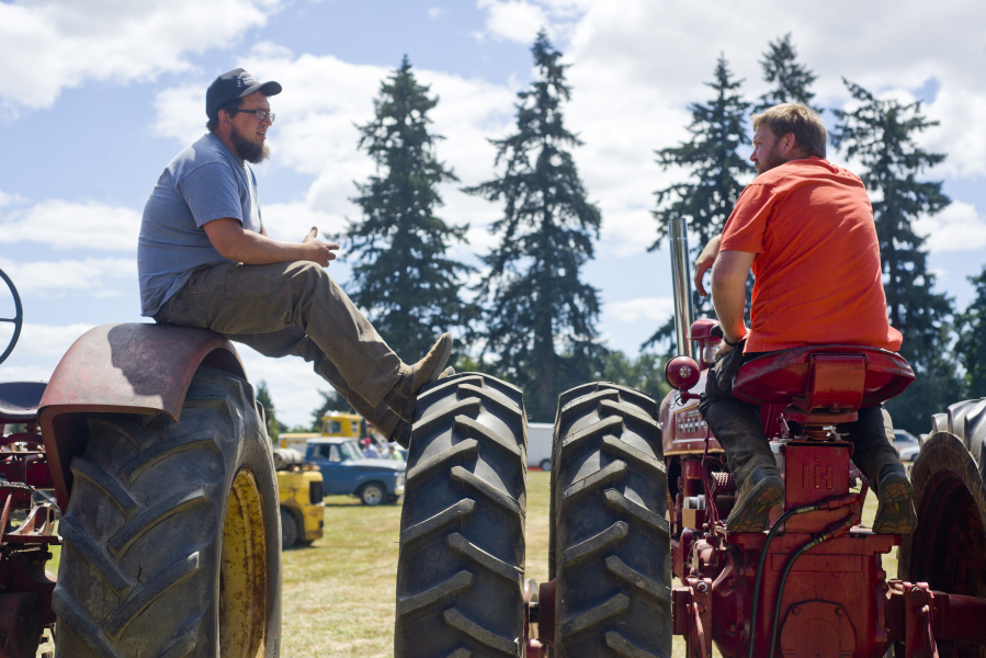 Bud Cronin, left, president of the Fort Vancouver Antique Equipment Association, chats with Lester Schurman, vice president of the association, atop antique tractors during the 23rd annual Rural Heritage Fair near Ridgefield Sunday. The event celebrates antique technology and techniques used on the farm and in daily life.