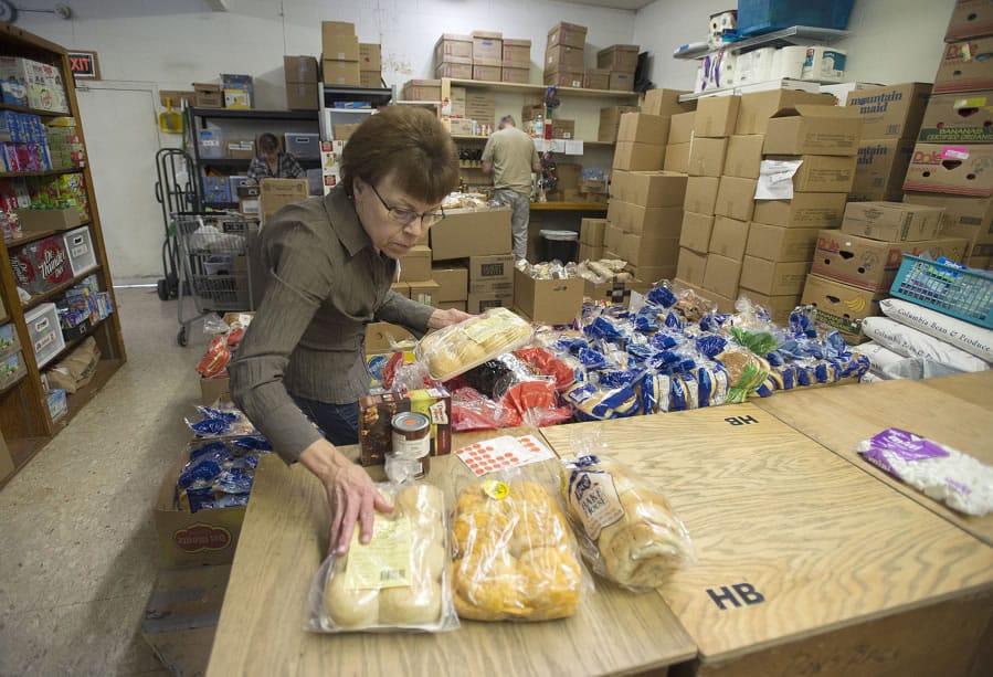 Volunteer Cindy Johnson sorts bread and other items in a crowded supply room at Clark County Adventist Community Services Monday morning.