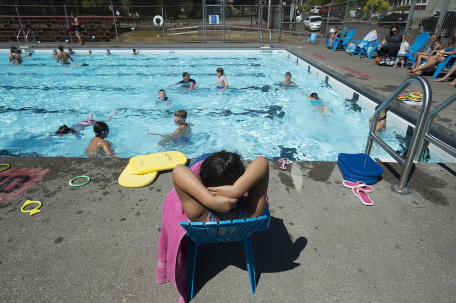 Zacil Castillo-Stengel, 5, of Camas, foreground, relaxes poolside while watching swimming lessons at the Crown Park pool. City officials are working on a master plan for upgrades to the pool, and one option replaces the pool with a new outdoor leisure pool, while the other replaces it with an interactive water feature with spray jets and bubblers.