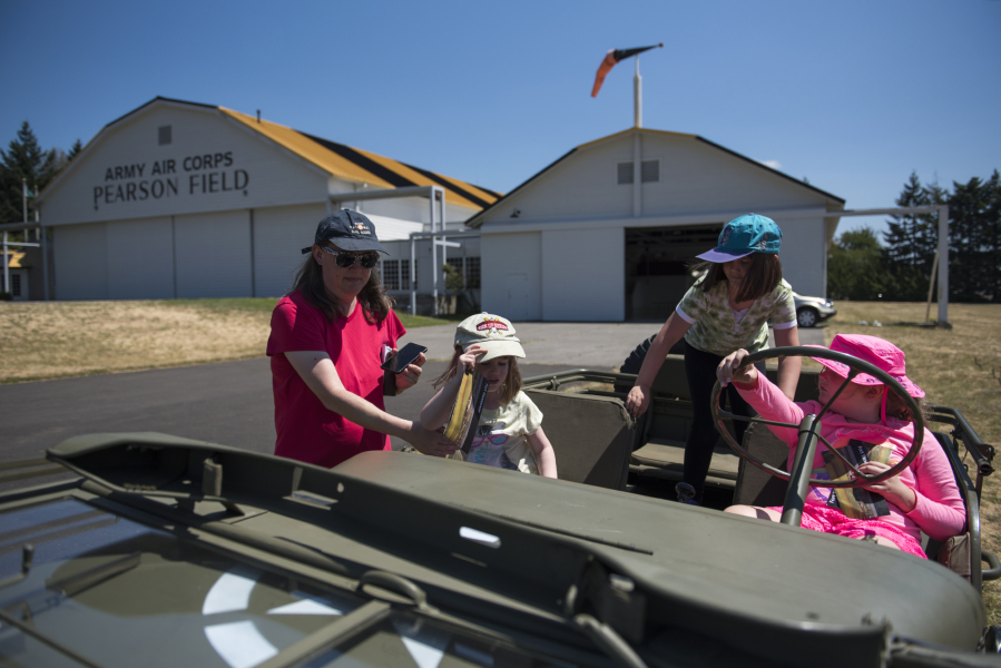 Susan Wood of Damascus, Ore., left, helps her daughter Emilia Wood, 5, into a 1945 Willys Jeep with her sister Elora Wood, 7, and their friend Claire Zielke of Portland, 7, at the 113th Cavalry Living History Group encampment just west of Pearson Air Museum on Friday afternoon. The encampmnt continues toay from 9 a.m. to 5 p.m.
