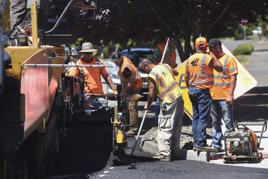 A crew from Lakeside Industries paves Southeast Norelius Drive at the intersection of Southeast 150th Avenue on Wednesday. The work is part of a new effort by Vancouver to repair failing residential streets.