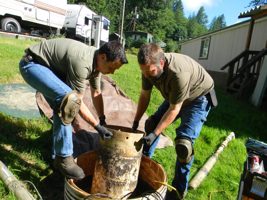 Ronnie Tamez, the owner of First Call Septic Service, and Chris Gross, a technician, pull the pump out of a septic system in a mobile home park in north Clark County. If something isn’t working, the pump will set off alarms, to the annoyance of the park’s residents.