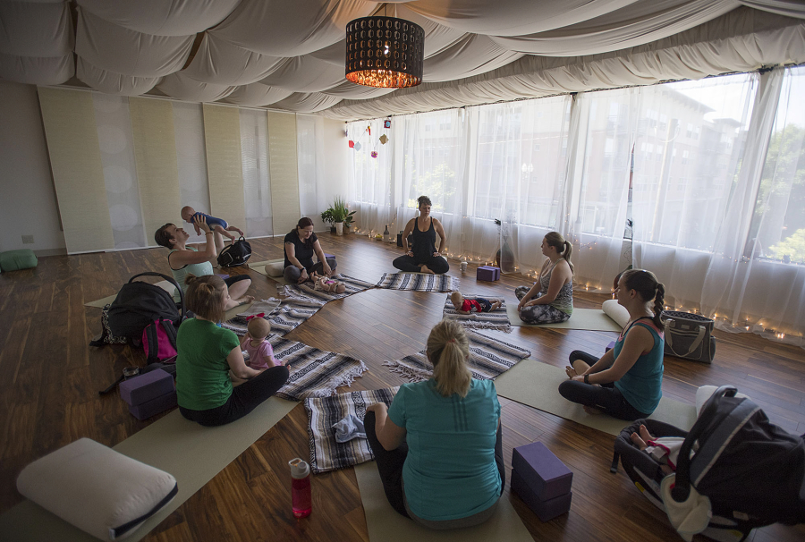 Daniele Strawmyre, top center, leads women through her Mommy and Me Yoga class on June 30 at Vancouver Wellness Studio. The class is open to women at least four weeks postpartum and their babies.
