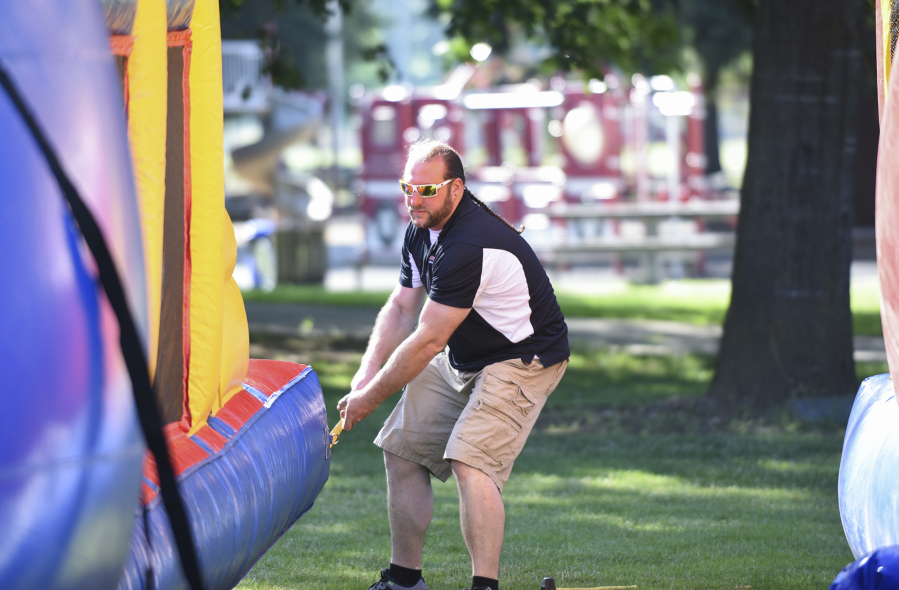 Ian Manheimer, owner of Bounce-N-Battle Inflatable Party Rentals in Vancouver, secures a bounce house before an event at Marshall Recreation Center.