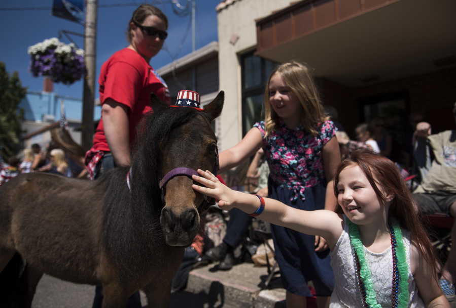 Baylee Long, 9, center, and Maddy Sanford, 8, right, pet a miniature horse during the Wild, Wild, West 4th of July parade in downtown Ridgefield on Tuesday afternoon.