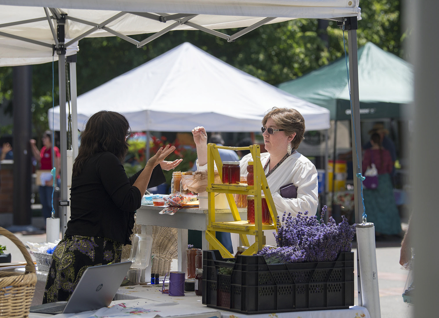 Danielle Davis, left, of Give Us A Buzz, talks with customer Rachel Belveal, who works at the Clark County Treasurer’s Office, at the Franklin Street Farmers Market on Wednesday afternoon. The market debuted Wednesday and will take place every Wednesday through August.
