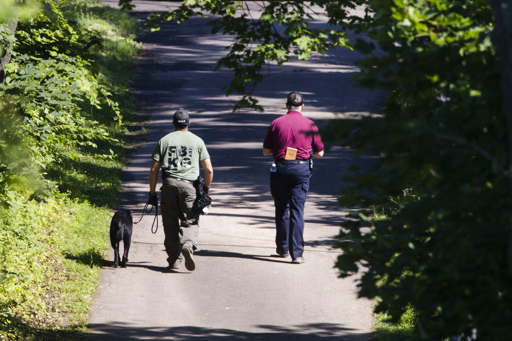 Investigators walk up a blocked off drive way, in, Solebury, Pa., as the search continues Wednesday, July 12, 2017, for four missing young Pennsylvania men feared to be the victims of foul play.