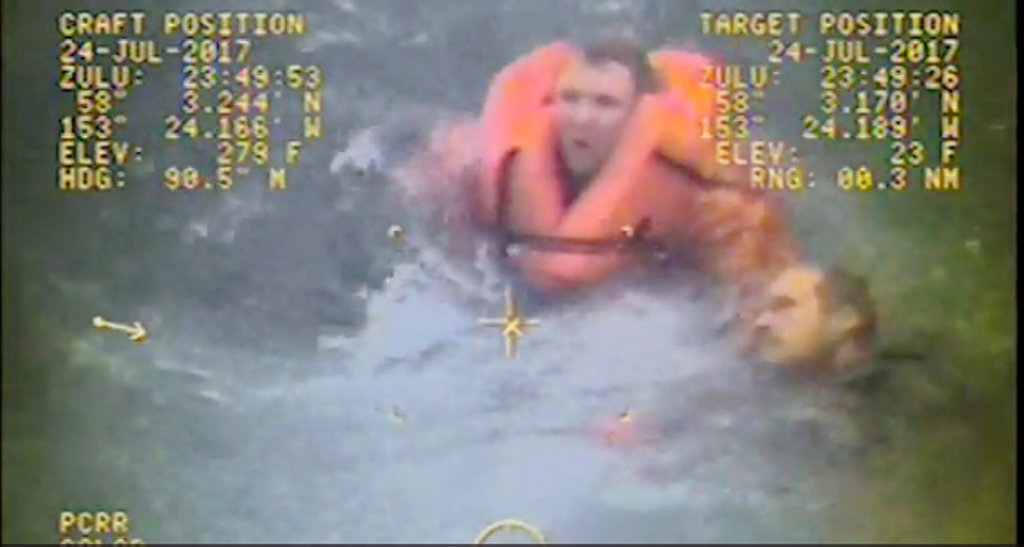 In this still image from video taken on Monday, July 24, 2017, by the Coast Guard, the captain of the fishing vessel Grayling, left, rescues one of his crewmen after the vessel capsized in the Kupreanof Strait near Raspberry Island, Alaska,. The captain jumped into cold, choppy waters to save two of his crew members after their vessel capsized off the Alaska coast. (William Colclough/U.S.