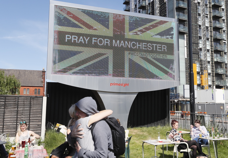 A couple embrace under a billboard in Manchester in England on May 237, the day after the suicide attack at an Ariana Grande concert that left more than 20 people dead . British police said Thursday that the man who bombed an Ariana Grande concert in Manchester wasn’t part of a large network, but other people involved in the attack may still be at large.