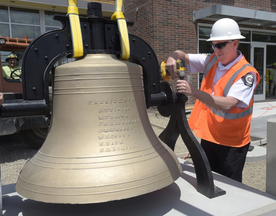 Fire Chief John Bradner fastens down the restored bell at the new Fire Station 11 in Albany, Ore., June 28.