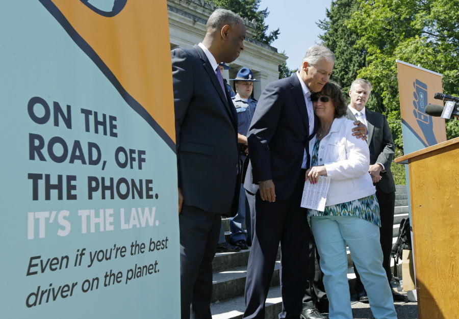 Washington Gov. Jay Inslee, center, comforts Tina Meyer, second from right, Monday after Meyer spoke about her death of her son, Cody Meyer, who was hit by a car driven by a distracted driver in 2015 while he was working as a construction flagger near Issaquah. Meyer and Inslee spoke during a press event at the Capitol in Olympia to raise awareness of Washington state’s new law prohibiting the use of nearly all phones and mobile devices while driving. The law, which is part of the Driving Under the Influence of Electronics Act, goes into effect Sunday. (AP Photo/Ted S.