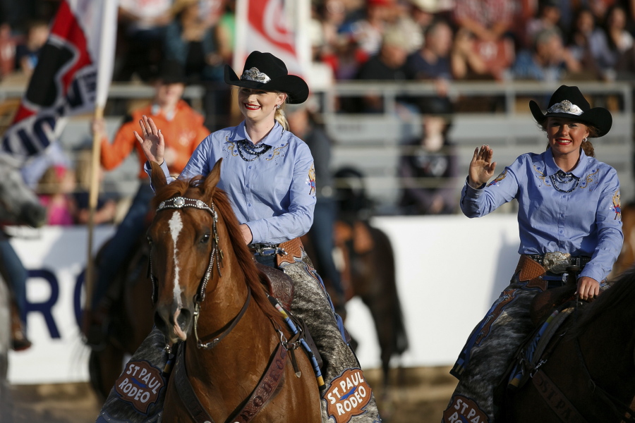 In a Thursday, June 29, 2017 photo, St. Paul Rodeo Princesses Morgan Spear and Britney Norby wave to the crowd as they ride in the Grand Entry parade for the rodeo’s first night. (Molly J.