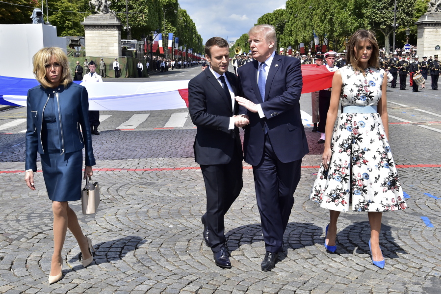 French President Emmanuel Macron, second from left, shakes hands with President Donald Trump while first lady Melania Trump and Brigitte Macron, left, walk on the sides after the Bastille Day military parade Friday in Paris.