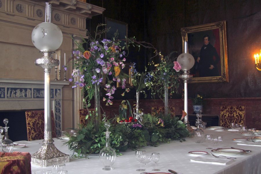 This July 6, 2011 photo provided by Dean Fosdick taken at the Biltmore Estate near Asheville, N.C., shows a dining room table set for a dinner party. It integrates a huge floral centerpiece with a number of accessories including glassware, tableware and antique lamps. Tablescaping is a feast for the eyes and brings nature into the dining room.