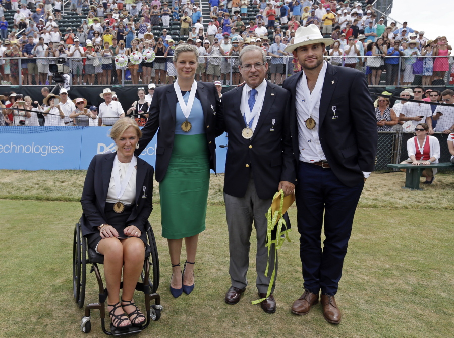 Tennis Hall of Fame inductees, from left, Monique Kalkman van den Bosch of the Netherlands, Kim Clijsters of Belgium, journalist Steve Flink of the United States and Andy Roddick of the United States pose at center court during enshrinement ceremonies at the International Tennis Hall of Fame, Saturday, July 22, 2017, in Newport, R.I.