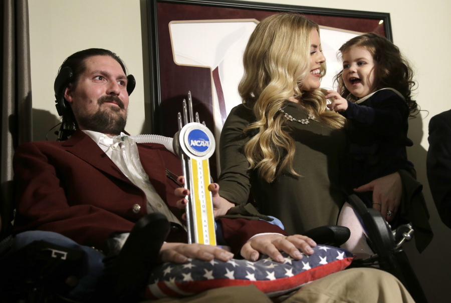 Former Boston College baseball captain Pete Frates, left, appears with his wife Julie, center, and two-year-old daughter Lucy, right, moments after he was presented with the 2017 NCAA Inspiration Award, at their home in Beverly, Mass.