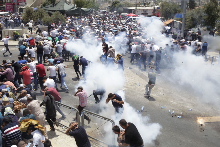 Palestinians run from tear gas thrown by Israeli police officers Friday outside Jerusalem’s Old City. Israel police severely restricted Muslim access to a contested shrine in the Old City to prevent protests over the installation of metal detectors at the holy site.