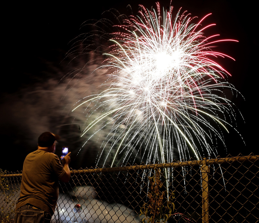 A man watches a fireworks display for Independence Day at Worlds of Fun amusement park Monday in Kansas City, Mo.