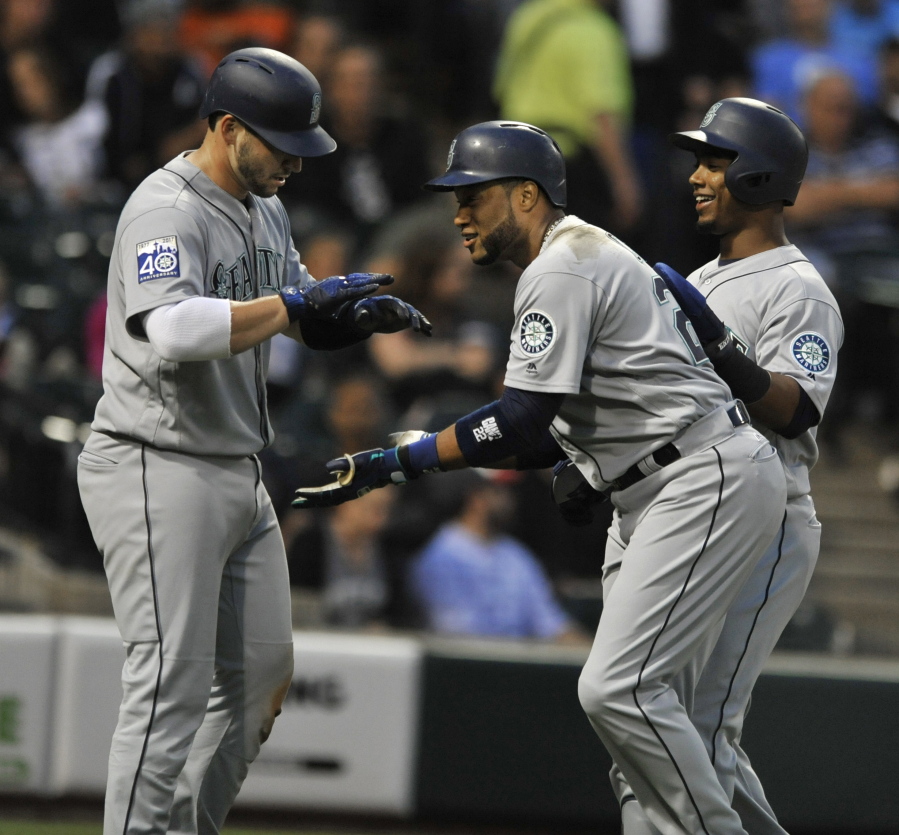 Seattle Mariners’ Robinson Cano center, celebrates with teammates Jean Segura, right, and Nelson Cruz, left, at home plate after hitting a three-run home run during the third inning of a baseball game against the Chicago White Sox, Friday, July 14, 2017, in Chicago.