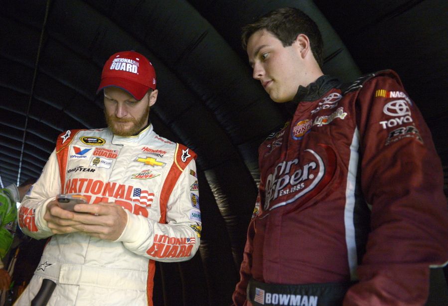 FILE - In this July 5, 2014, file photo, Alex Bowman, right, watches as Dale Earnhardt Jr. sends out a tweet while waiting under a tunnel for driver introductions to begin before a NASCAR Sprint Cup Series auto race at the Daytona International Speedway, in Daytona Beach, Fla. Dale Earnhardt Jr. got the replacement he wanted. Alex Bowman got his dream job. Hendrick Motorsports announced Thursday, July 20, 2017, that the 24-year-old Bowman will replace one of the series’ biggest stars in the No. 88 car next season after Earnhardt retires.(AP Photo/Phelan M.
